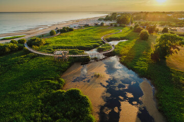 Wooden hiking trail on the wetland and observation tower, deck with beautiful views. Parnu, Estonia, during sunset captured from birds eye view.