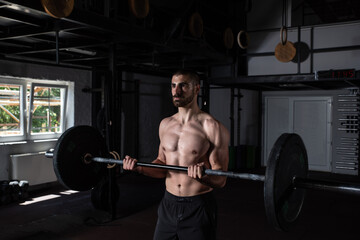Fototapeta na wymiar Young active sweaty muscular fit strong man with big muscles doing biceps curly with heavy barbell weight in the gym as hardcore workout cross training real people exercise