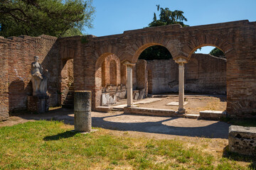 Ostia Antica, Italy Ancient Roman ruins, detail of an architectural structure with marble arches and columns, capitals and toga statue, Ostia Antica archaeological park, Roman port Tiber.
