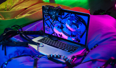 A set of BDSM toys for sex on a laptop on a bright neon background