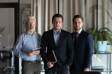 Confident professionals, lawyers, bankers, financial expert team portrait. Senior and young male employees standing together in office, looking at camera. Business leaders head shot.