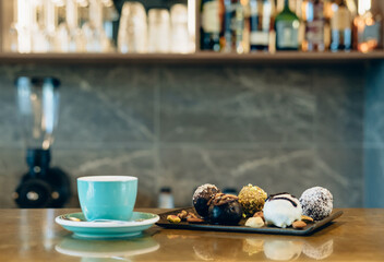 A Group of Healthy Protein Balls with Nuts and Green Cup of Espresso Coffee on Golden Bar Counter in a Cafe