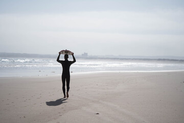 the guy carries a surfboard on the beach. Concept: entertainment, sports, readiness