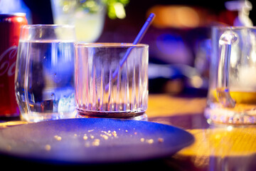 shot of whiskey with soda fizzing bubbling in an elegant glass with out of focus food items all...