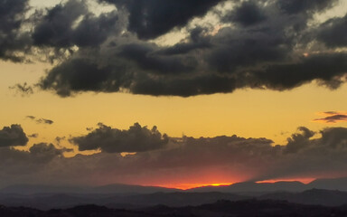 Fototapeta na wymiar Tramonto sulle montagne e le valli dell’Appennino con grandi nuvole colorate cariche di pioggia