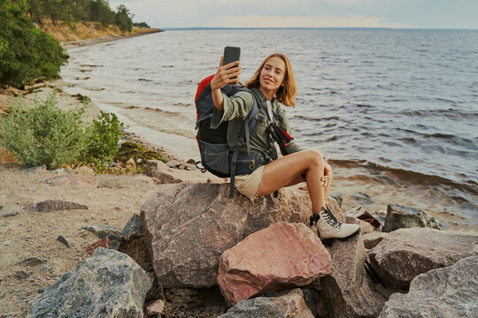 Backpacker taking selfie on a river shore