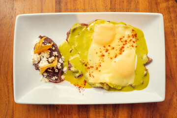 Gourmet green eggs with beans. Traditional Mexican food with beans. Traditional Mexican gourmet food concept, traditional green eggs.