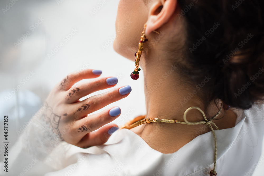 Wall mural back view of young indian bride in earring wearing necklace on white