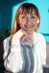 Portrait of a young beautiful red-haired girl in a cafe on a sunny day, close-up.