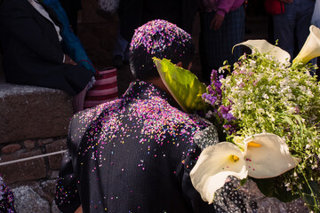 The groom is covered by confetti by onlookers at a marriage in Peru