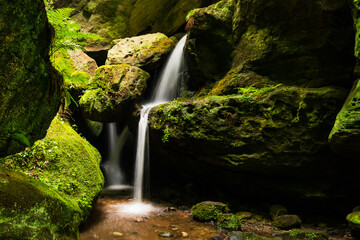 Fototapeta premium Wasserfall bei den Schwedenlöchern in der Sächsischen Schweiz mit Moos bedeckten Felsen