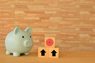Piggy bank, arrow up and target symbol on wooden blocks.