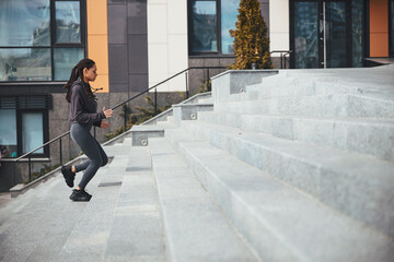 Sportswoman with trendy Afro bunches ascending the concrete steps