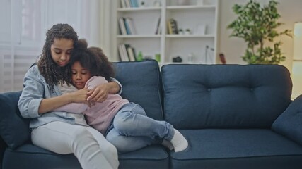 Caring african teen girl hugging and comforting sad little sister, family love