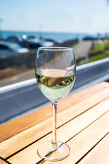 Glass of white wine served on outdoor terrase with seaview, summer vacation
