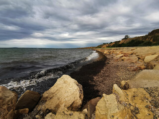 Dark storm clouds over the Sea of Azov. Taman, Krasnodar Territory, Russia. Stones, waves, low dark clouds.