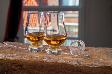 Dram of single malt scotch whisky served in tasting glass with view on old window and houses