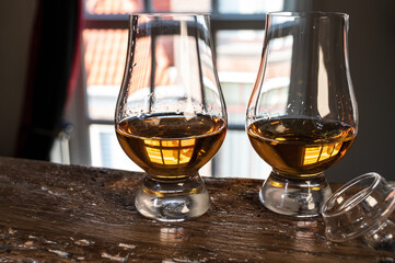 Dram of single malt scotch whisky served in tasting glass with view on old window and houses