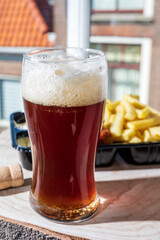 Drinking dark beer with fried cod fish fillet and french fried potatoed chips with view on street in old Zierikzee town, Zeeland, Netherland