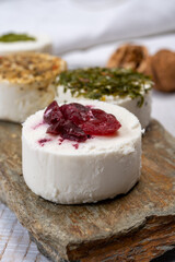 Cheese collection, variety of fresh white soft goat French cheeses with aromatic herbs, berries and green pesto