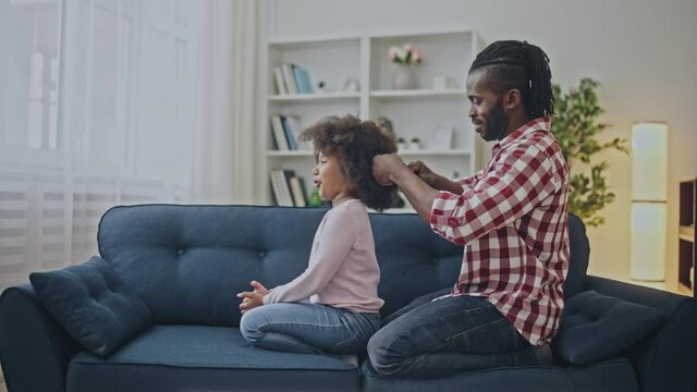 Caring father combing afro hair of little daughter, morning routine, parent love