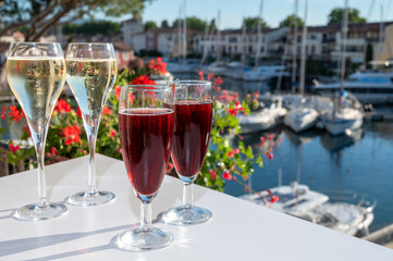 Summer party with kir royal cocktail, tasting of French brut champagne sparkling wine and cold creme cassis in glasses in yacht harbour of Port Grimaud near Saint-Tropez