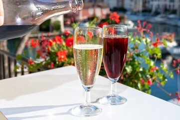 Summer party with kir royal cocktail, pouring of French brut champagne sparkling wine and cold creme cassis in glasses in yacht harbour of Port Grimaud near Saint-Tropez
