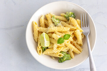 Penne Pasta with Broccoli Garnished with Lemon and Basil  Directly Above Horizontal Photo on White Background