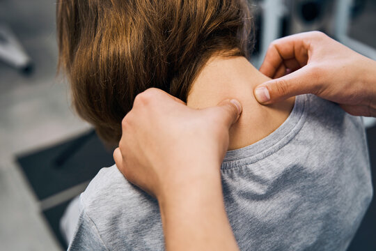 Osteopath in uniform edits cervical spine vertebrae of young female patient on massage bed closeup