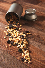 recipiente con manies y pasas de uva volcadas sobre una mesa de madera