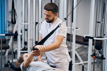 Pediatric physiotherapist working with little girl in rehabilitation center on elastic simulators