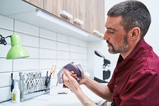 Professional optician cleaning lens for glasses in workshop