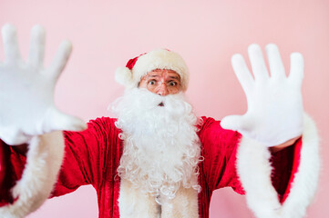 Man dressed as Santa Claus looking at camera with palms in stop sign
