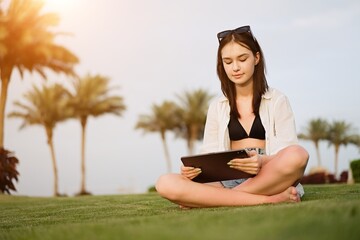 Cut teenager girl using tablet on the background of the beach. Summer vacation concept, studying online with tablet, distance learning, self education, beach work                 
