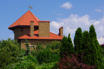 Fototapeta premium House with brown roof tiles in a beautiful green garden.