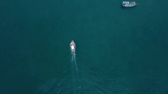 Aerial view. Beautiful shot of the colorful fishing boat going to the port.  Turquoise water of the sea in a paradise of a tropical island the stunning nature somewhere in southeast Asia.