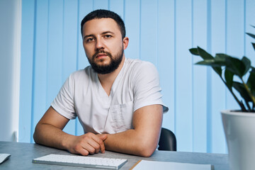 Portrait of male physician with self-confidence at private clinic office. Interior of workplace