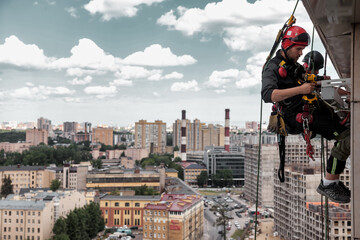 Industrial mountaineering worker hangs over residential building