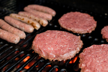 Hamburgers on Grill with Dancing Flames Cooked to Perfection.A closeup of some fresh and juicy hamburgers cooking on the grill.Beef burgers being cooked