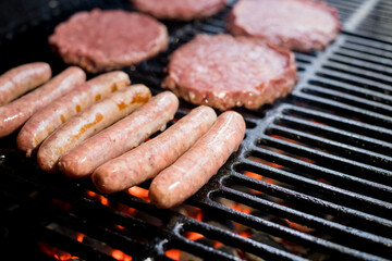 Hamburgers on Grill with Dancing Flames Cooked to Perfection.A closeup of some fresh and juicy hamburgers cooking on the grill.Beef burgers being cooked