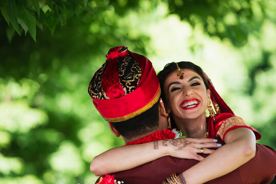 Back View Of Indian Man In Turban Hugging Happy Bride In Traditional Headscarf