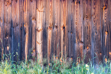 Old, weathered, beautiful, wooden planks. Green, fresh grass in the foreground. Texture effect.