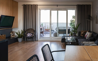 Modern living room with space and big window. Wooden floor and wall with tv. Interior of room in apartment.
