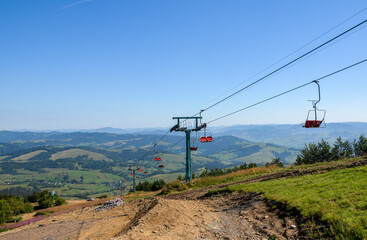 Fototapeta na wymiar Empty red chairlift in the mountains at ski resort Pylypets during summer clear day. Carpathians, Ukraine