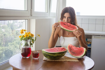 Happy European woman holding large slices of watermelon, bright red berry on the table and in the woman's hands.  © malyutinaanna