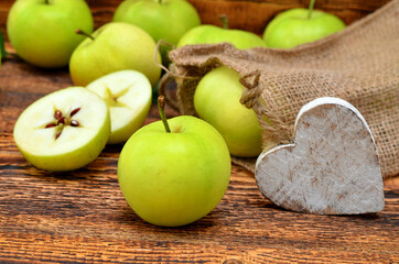 green apples on the table and a wooden heart