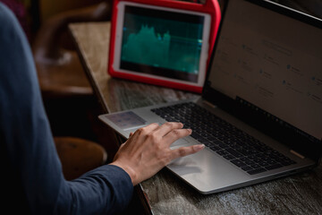 Manos de una mujer morena con una computadora viendo gráficos del mercado en linea 