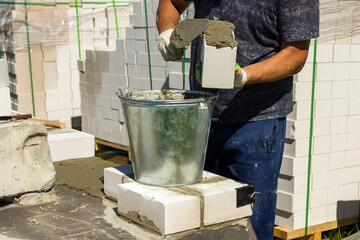 the builder applies cement mortar to the brick during the construction of the brickwork
