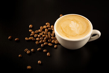 
A cup of coffee and beans on the black background. top view