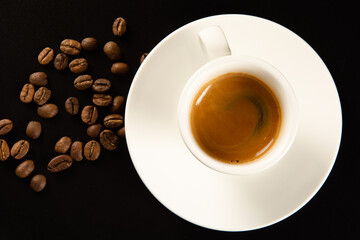 cup of espresso and coffee beans on a black background, top view